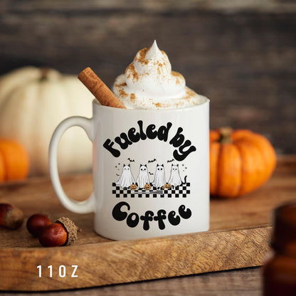 A ceramic mug themed with cats in ghost costumes and the saying "Fueled by coffee" is the perfect fall treats and thanksgiving favors
