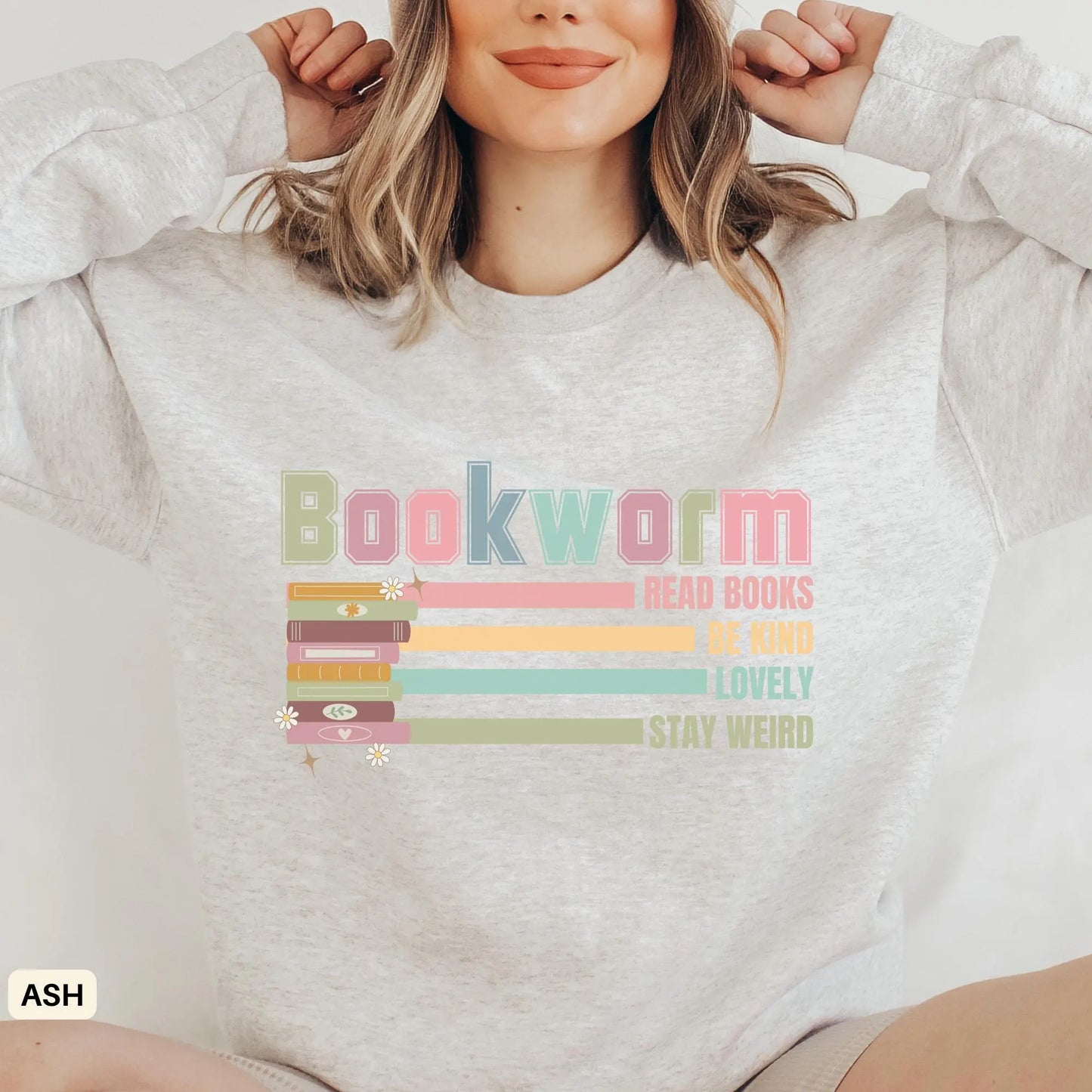 A woman wearing a gray sweatshirt with the word 'Bookworm' and various book-related phrases embroidered on the front.