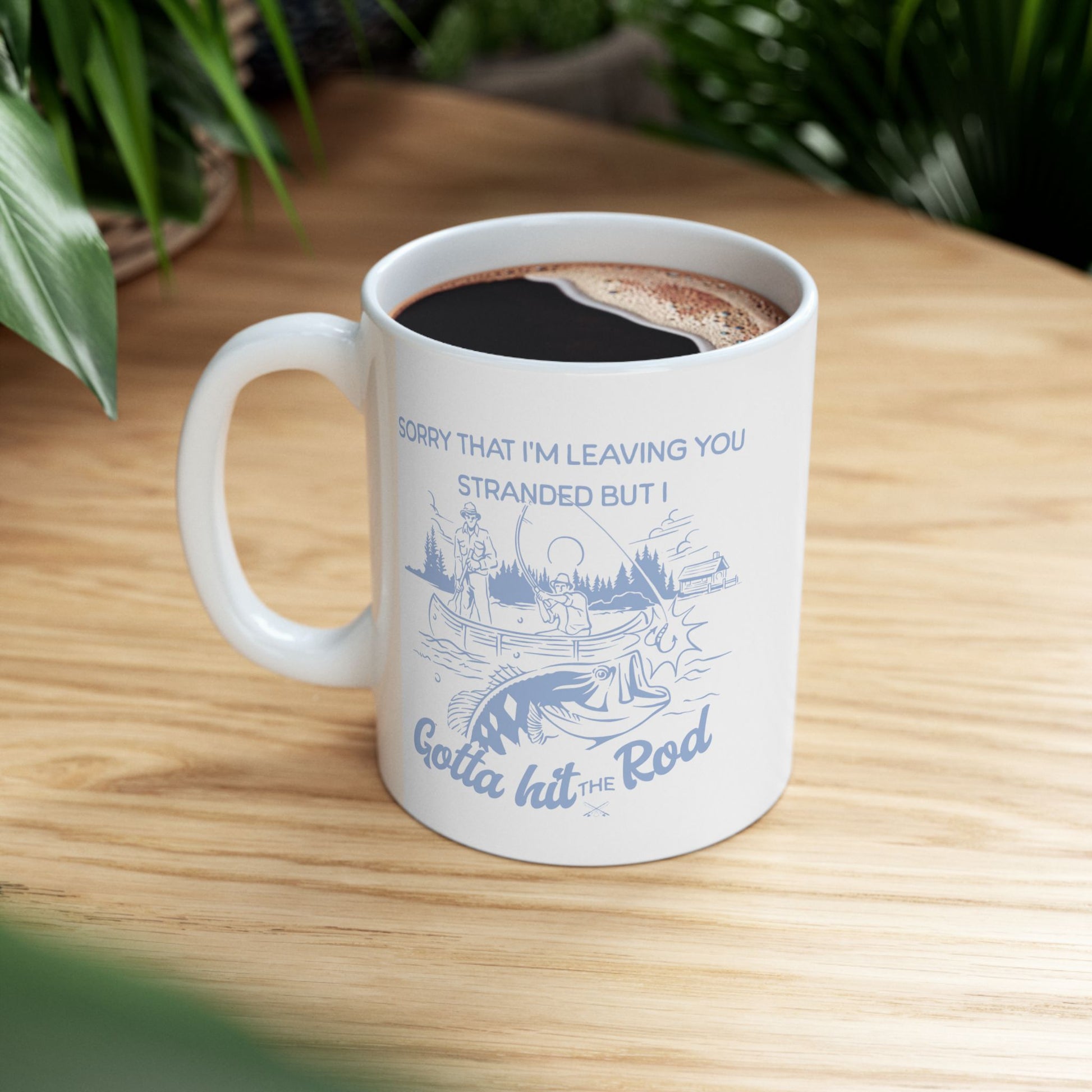 11 OZ white CERAMIC COFFEE MUG WITH A FISHING DESIGN OF MENS AND FISH IN A LAKE AND THE FUNNY PHRASE "SORRY THAT I'M LEAVING YOU STRANDED BUT I GOTTA GIT THE ROD"